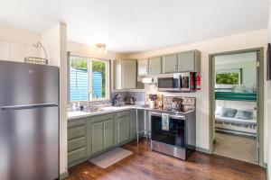 a kitchen with green cabinets and a stainless steel refrigerator at Ocean Breeze & Clam Pad in Ocean Shores