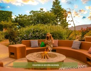 a woman sitting on a couch next to a fire pit at Hotel Boutique Valle de Guadalupe & Spa in Valle de Guadalupe