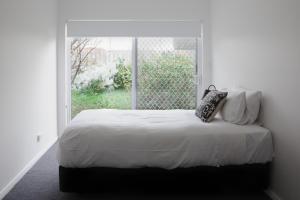 a white bedroom with a bed with a window at Battery Point Manor in Hobart