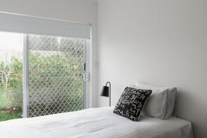 a white bedroom with a bed and a window at Battery Point Manor in Hobart