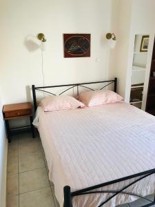 a bedroom with a bed with pink pillows and a clock on the wall at Cozy Apartment Near City Center in Preveza