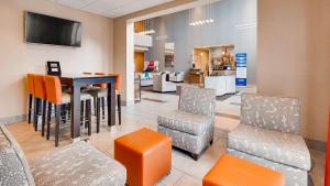 a waiting room with chairs and a table and a tv at Best Western Plus Atrium Inn & Suites in Clarksville