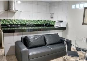 um sofá de couro preto numa cozinha com uma mesa em Maresia Flats em Fortaleza