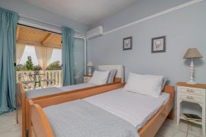 two beds in a bedroom with a balcony at Villa Zakynthian treasure in Vanáton