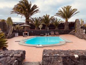 a swimming pool in a yard with palm trees at Vivienda vacacional Julia in La Asomada