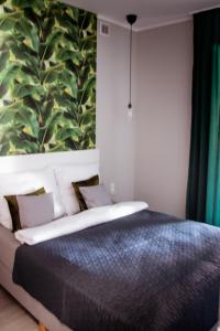 a bedroom with a bed with a large leaf mural on the wall at Apartamenty Długa 6 in Bydgoszcz