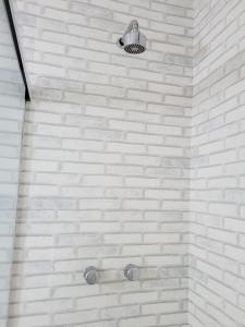 ducha con paredes de ladrillo blanco y luz en Apartamento quadra da praia em Copacabana, en Río de Janeiro
