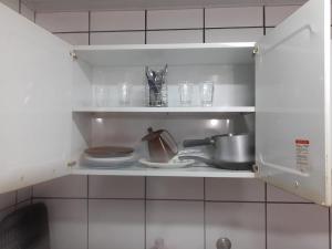 uma prateleira de cozinha com pratos e utensílios em Apartamento Beira Mar - Vila Guilhermina em São Paulo