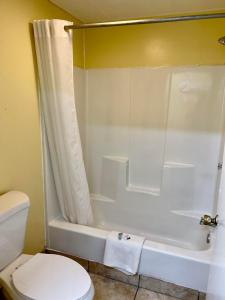 a bathroom with a white tub and a toilet at Economy Motel in Galloway