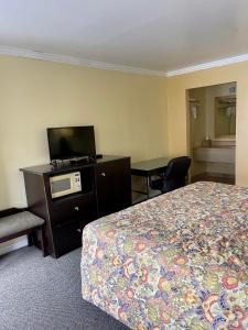 Habitación de hotel con cama y TV de pantalla plana. en Economy Motel en Galloway