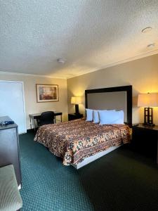 Habitación de hotel con cama grande con almohadas blancas en Economy Motel, en Galloway