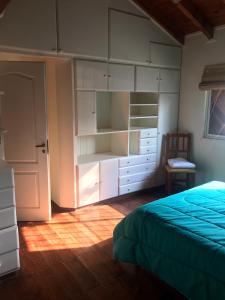 Un dormitorio con armarios blancos y una cama y una silla. en Quinta El Molino, en San Pedro