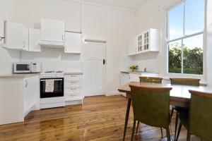 a kitchen with white cabinets and a wooden table at Avalon Farm Stay in The Rock