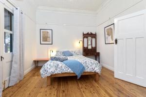 a white bedroom with a bed and a wooden floor at Avalon Farm Stay in The Rock