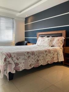 1 dormitorio con 1 cama grande y pared azul en Alem Do Horizonte, en Iquique