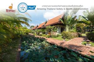 a garden with a pond in front of a house at Khaolak Bhandari Resort & Spa - SHA Extra Plus in Khao Lak