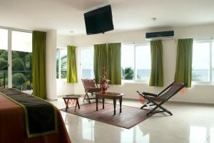 a bedroom with a bed and chairs and windows at Kay Hotel in Playa del Carmen