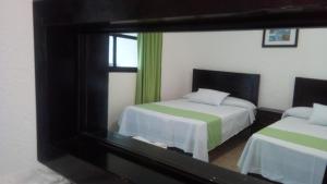 a reflection of a bedroom with two beds in a mirror at Hotel D'Lina Princess Suites in San Cristóbal de Las Casas