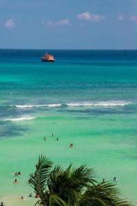 Gente tendida en la playa con un barco en el océano en Hotel Kay Adults Only, en Playa del Carmen