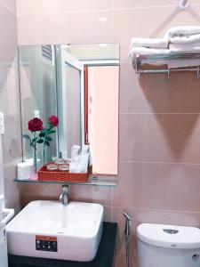 a bathroom with a sink and a mirror and a toilet at Victory Airport Hotel in Ho Chi Minh City
