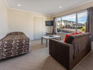 a bedroom with a couch and a bed and a window at Cottage Park Thermal Motel in Tauranga