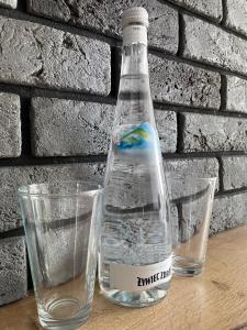 a bottle of water next to two glasses on a table at Apartment 2-Rooms-Garage-TV-Wifi in Poznań