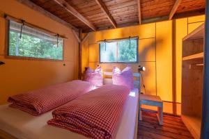 2 łóżka w pokoju z żółtymi ścianami i oknami w obiekcie Ferienpark Terrassencamping Süd-See w mieście Walchsee