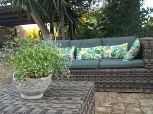 a wicker couch with pillows and a potted plant at Oasi di Campagna in Modica