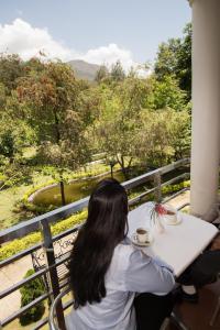 a woman sitting at a table on a balcony looking at a view at Park Village Resort by KGH Group in Kathmandu