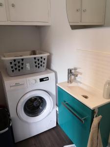 - un lave-linge dans une cuisine à côté d'un évier dans l'établissement Les baigneurs, à Merville-Franceville-Plage