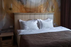 ウラジオストクにあるオーロラ パーク ホテルの白い枕と壁画付きのベッド