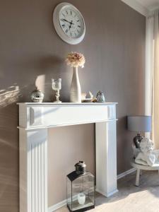 a white fireplace with a clock on a wall at FeWo Casa in Boizenburg