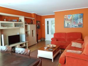 sala de estar con paredes de color naranja y sofá rojo en Mundaka Beach flat parking privado, en Mundaka