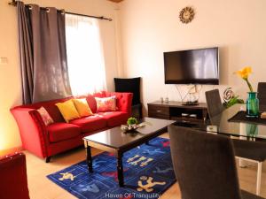 a living room with a red couch and a tv at Stay.Plus Milimani Apartment Kisumu in Kisumu