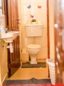 a small bathroom with a toilet and a sink at Stay.Plus Milimani Apartment Kisumu in Kisumu