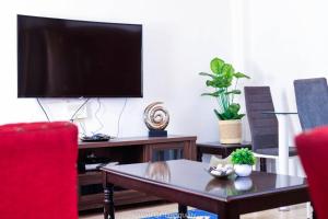 a living room with a tv and a coffee table at Stay.Plus Milimani Apartment Kisumu in Kisumu