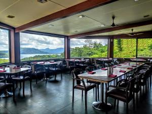 um restaurante com mesas e cadeiras e janelas grandes em Upper Deck Resort em Lonavala