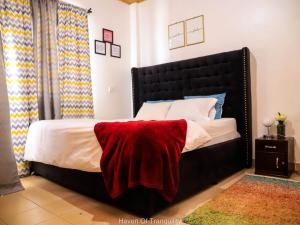 a bedroom with a large bed with a red blanket on it at Stay.Plus Milimani Apartment Kisumu in Kisumu