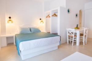 - une chambre blanche avec un lit et une table dans l'établissement Anemos Guest Apts, à Karpathos