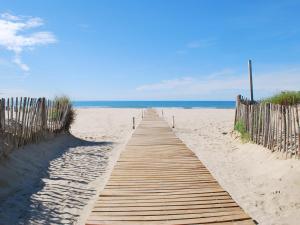 un camino de madera a la playa con el océano en el fondo en Appart - Suites Gaya Centre Ville en Montpellier