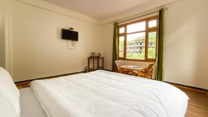a bedroom with a white bed and a window at Hotel KALPA in Kalpa