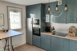 een keuken met blauwe kasten en een witte koelkast bij Appartement au lac du chateau in Flers-lez-Lille
