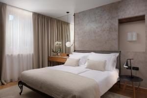 a bedroom with a large white bed and a desk at Malipiero Residence in Rovinj