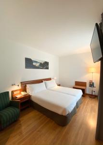 a bedroom with a large bed and a green couch at Hotel Zentral Gijón Rey Pelayo in Gijón