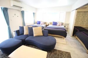 a room with four beds and a blue couch and a couch at Condominium Felicita Naha in Naha