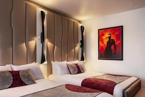 
a hotel room with a bed, a lamp and a painting on the wall at Disney's Hotel New York® - The Art of Marvel in Chessy
