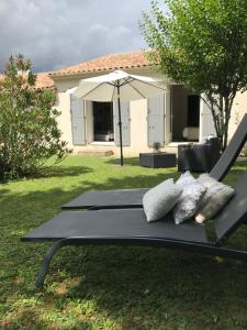 a bench with pillows and an umbrella in a yard at La Maison des Eaux Claires in Puymoyen