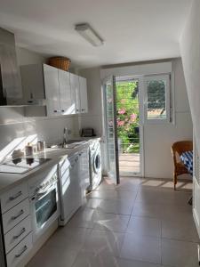 cocina blanca con fregadero y lavavajillas en Casa Rural Nacimiento del Huéznar - Tomillo 23, en San Nicolás del Puerto