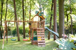 a wooden playground with a slide in a park at Lüneburger Heide - Ferienwohnung am Höpen in Schneverdingen