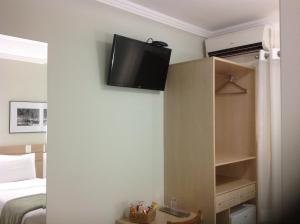 a room with a bed and a television on the wall at Upper Hotel in São Paulo